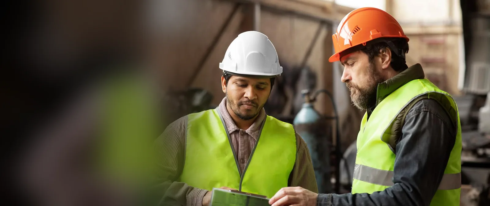 Two engineers in safety helmets reviewing a project on the factory floor